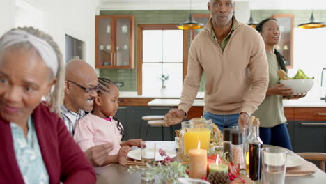 Happy-african-american-multi-generation-family-serving-food-at-thanksgiving-dinner,-slow-motion