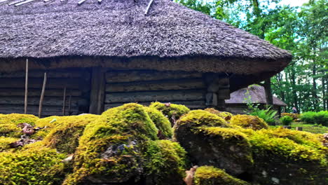 Antigua-Cabaña-De-Madera-Con-Techo-De-Caña-Junto-A-Rocas-Cubiertas-De-Musgo-En-El-Museo-Al-Aire-Libre