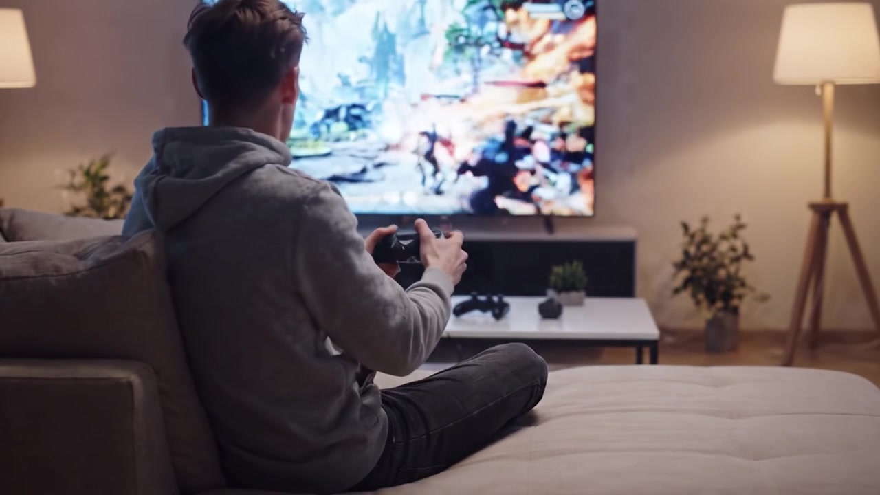 Impegnato in una sessione di gioco epica: un giocatore concentrato immerso nell'azione sul suo divano, catturando l'intensità del mondo virtuale che si dispiega sullo schermo.