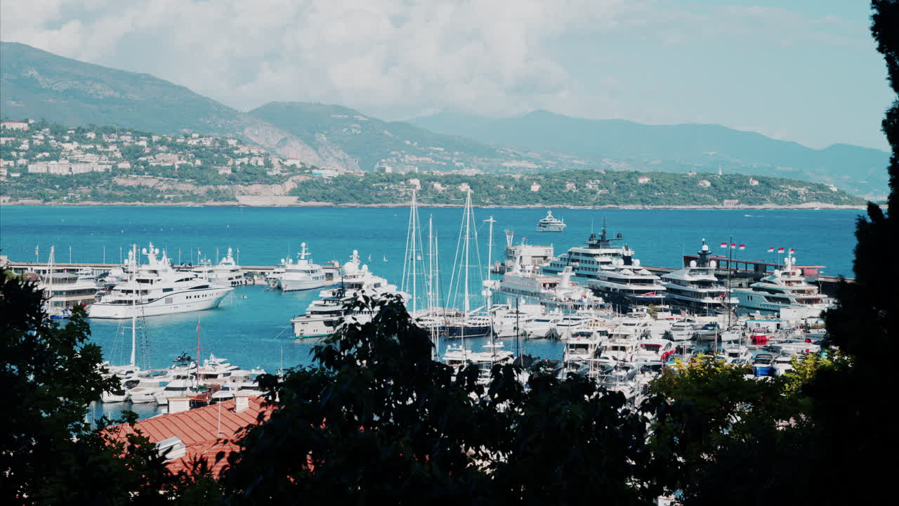 Aerial view of boats docked in the Monaco Marina with the skyline of the city on the background