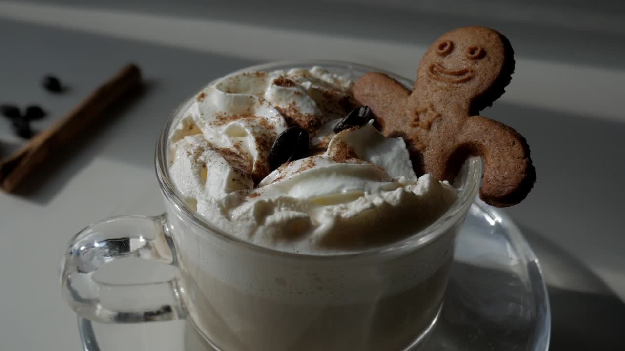 Macro close-up of gingerbread man cookie resting on top of whipped cream pumpkin spice latte under warm daylight