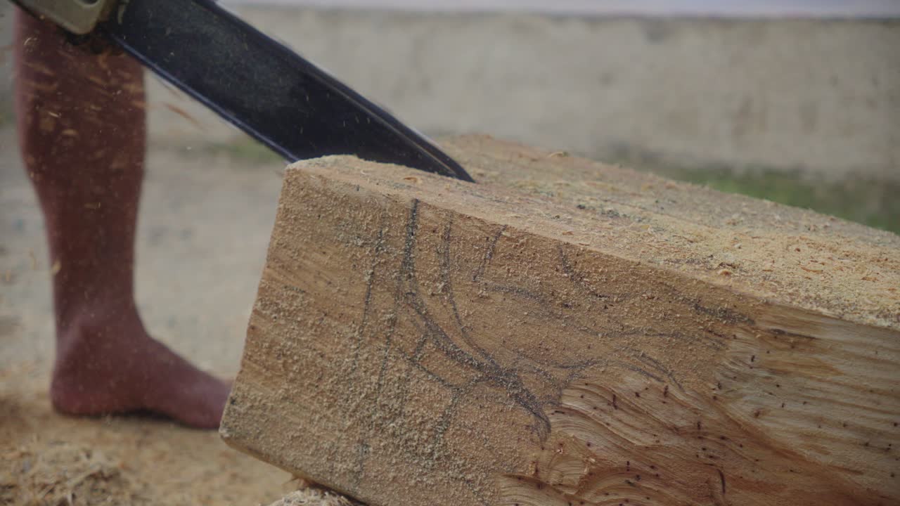 예술가 한 사람 이 체인 으로 나무 조각 을 자르고 있다