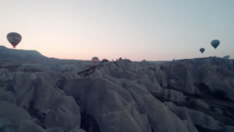 hot air balloons soar over cappadocia’s rocky landscape during sunrise