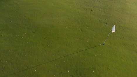 Pasando-Por-Encima-Y-Más-Allá-De-Una-Bandera-Blanca-En-Un-Campo-De-Golf-Verde