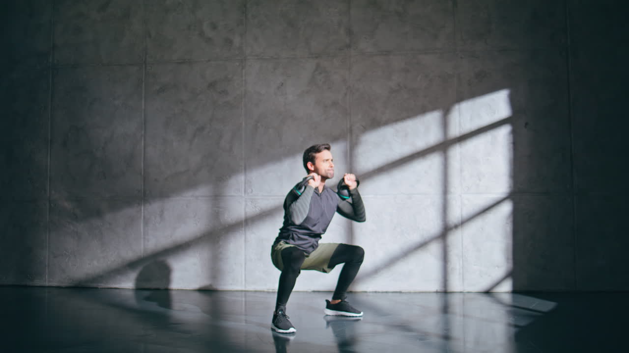 Un culturista muscoloso solleva un kettlebell facendo squat in palestra. Uomo sano che si allena