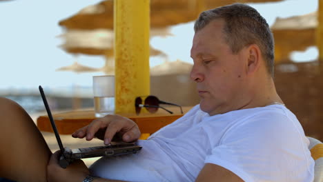 hombre con computadora portátil en la playa