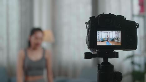 close up of a camera monitor recording asian trainer female in sports clothes doing yoga in high lunge pose while teaching exercise at home