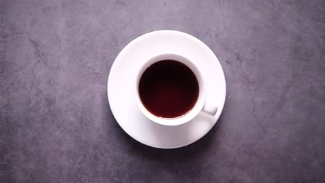 taza de té blanca con azúcar en la superficie oscura