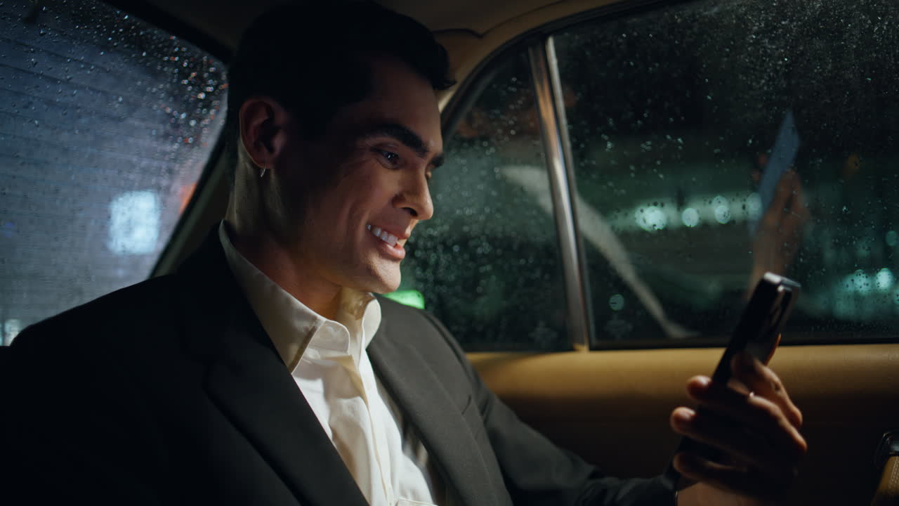 hombre de negocios regocijado desplazando el teléfono inteligente en el primer plano del vehículo. gerente de trabajo