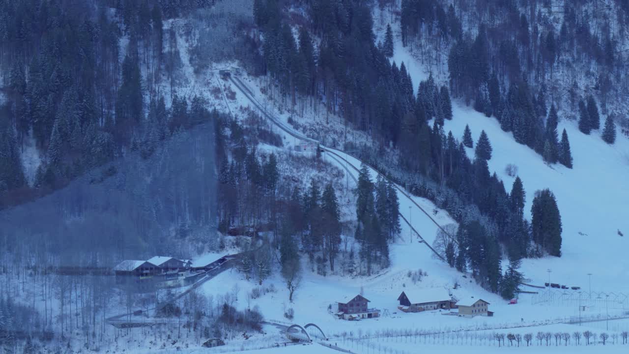 vista desde la ventana de vidrio de un teleférico que pasa por un pueblo alpino en el camino a la cima de la ladera nevada de engelberg, en brunni, suiza