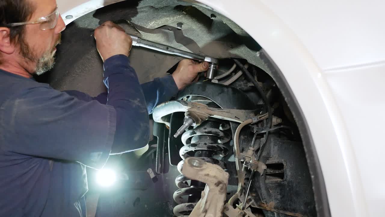 un mecánico usa una llave dinamométrica para apretar las tuercas del puntal superior