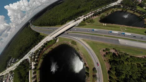 Drones-Aéreos-Empujan-A-Los-Autos-Del-Puente-Que-Pasan-Por-La-Carretera-Girando-Hacia-Una-Vista-De-Lente-De-Ojo-De-Pez