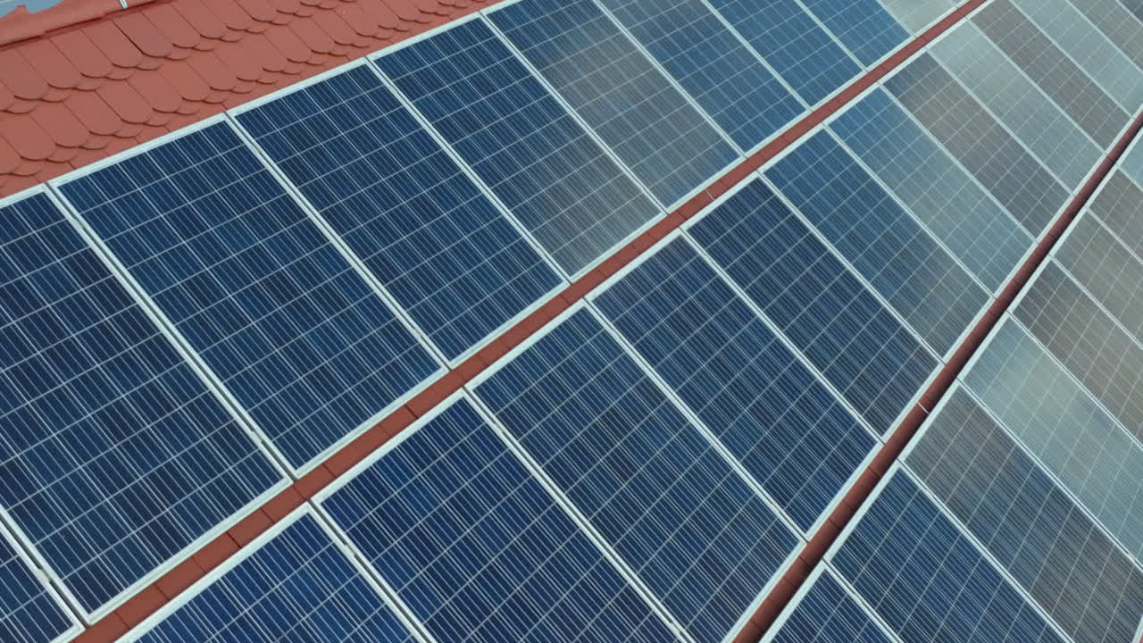 Serie di pannelli solari blu installati ordinatamente su un tetto con tegole arancioni, che catturano la luce solare e la convertono in energia pulita