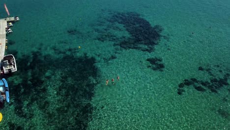 Drohnenaufnahmen-Mit-Klarem-Türkisfarbenem-Wasser-Des-Mittelmeeres,-Die-Kamera-Geht-Hoch,-Menschen-Schwimmen