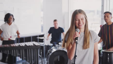 students at performing arts school playing in band at rehearsal