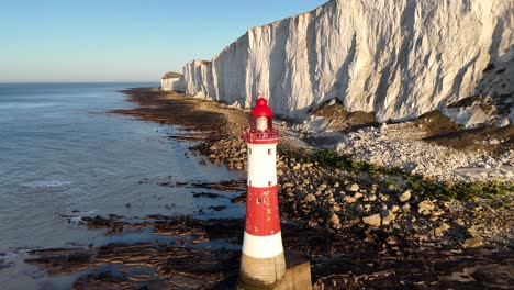 stunning aerial video of beachy head lighthouse, white cliffs, and rocky coastline in sussex, england. smooth pull-away shot revealing stunning coastal views.