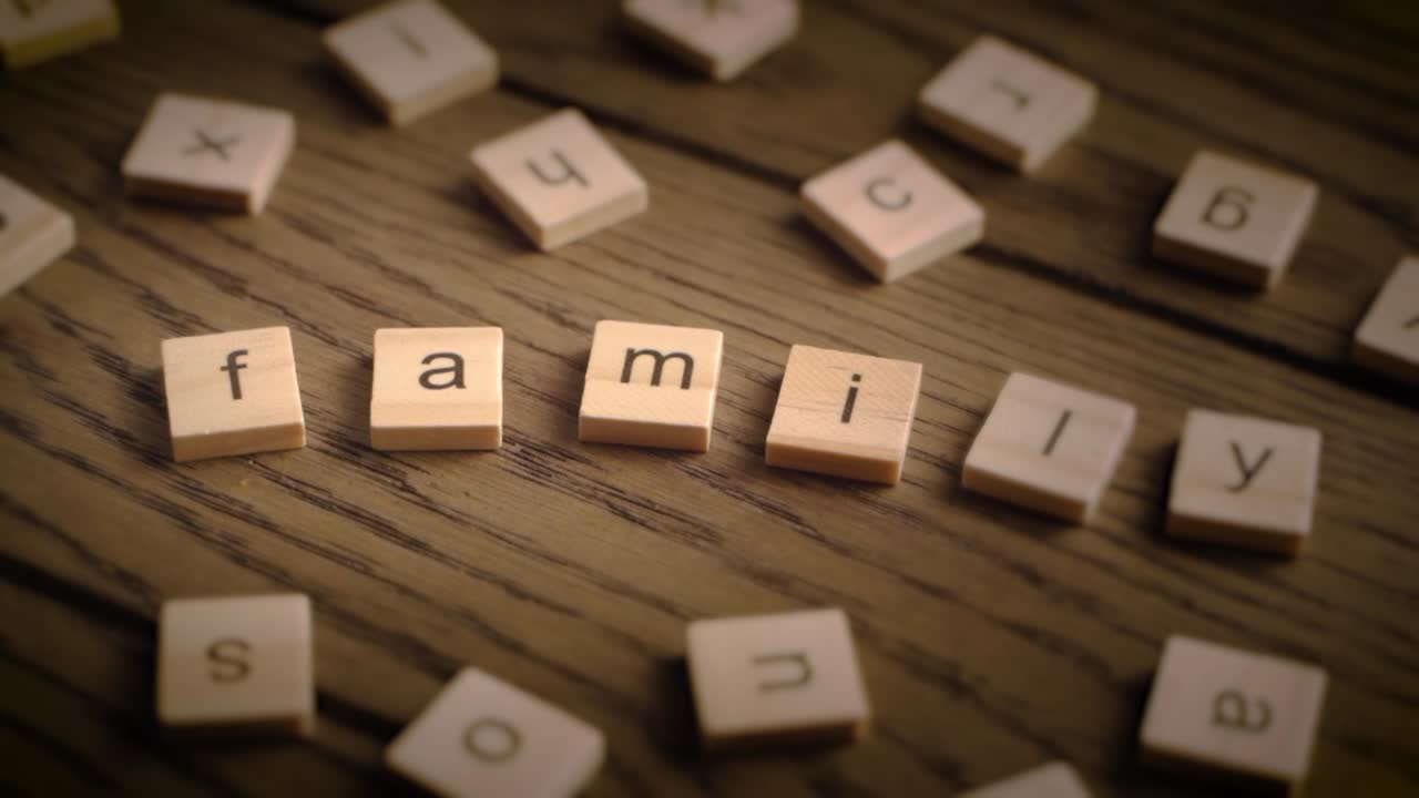 Wooden tiles spell the word family as the camera gently pans across a rustic wooden surface in warm lighting.