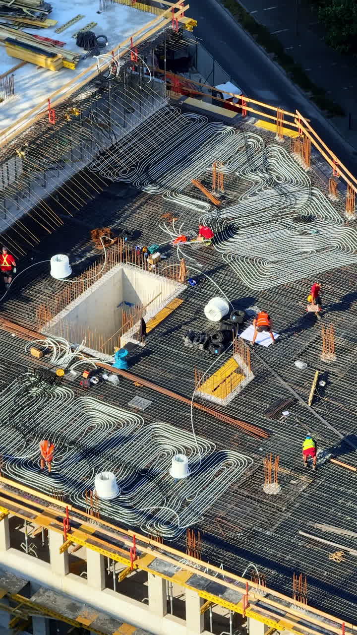 Workers finish rooftop structure. Workers lay rebar and prep for concrete on a rooftop at a construction site during the day