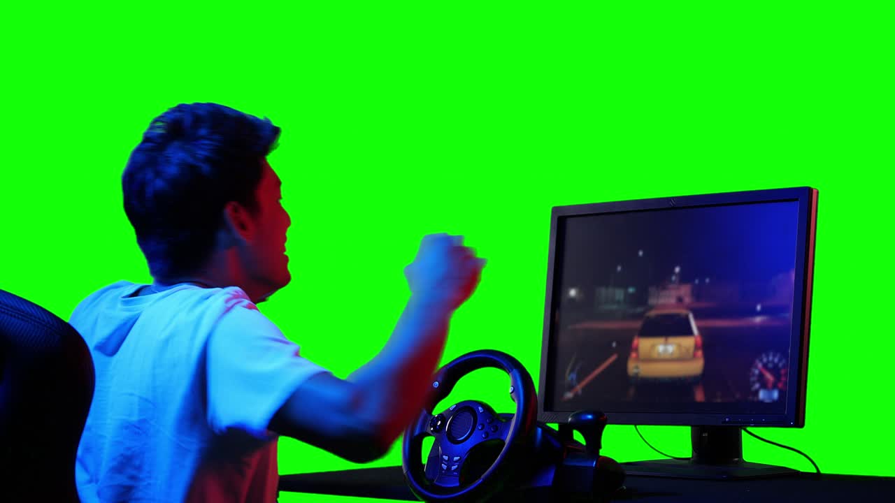 Asian gamer man playing game and looking at screen. Asian man controlling console with joysticks. Handsome man leisure digital game with green screen or chroma key background.