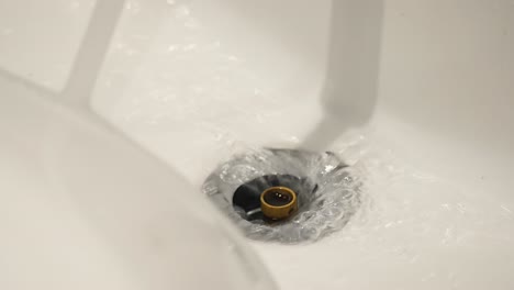 water swirling down a white drain
