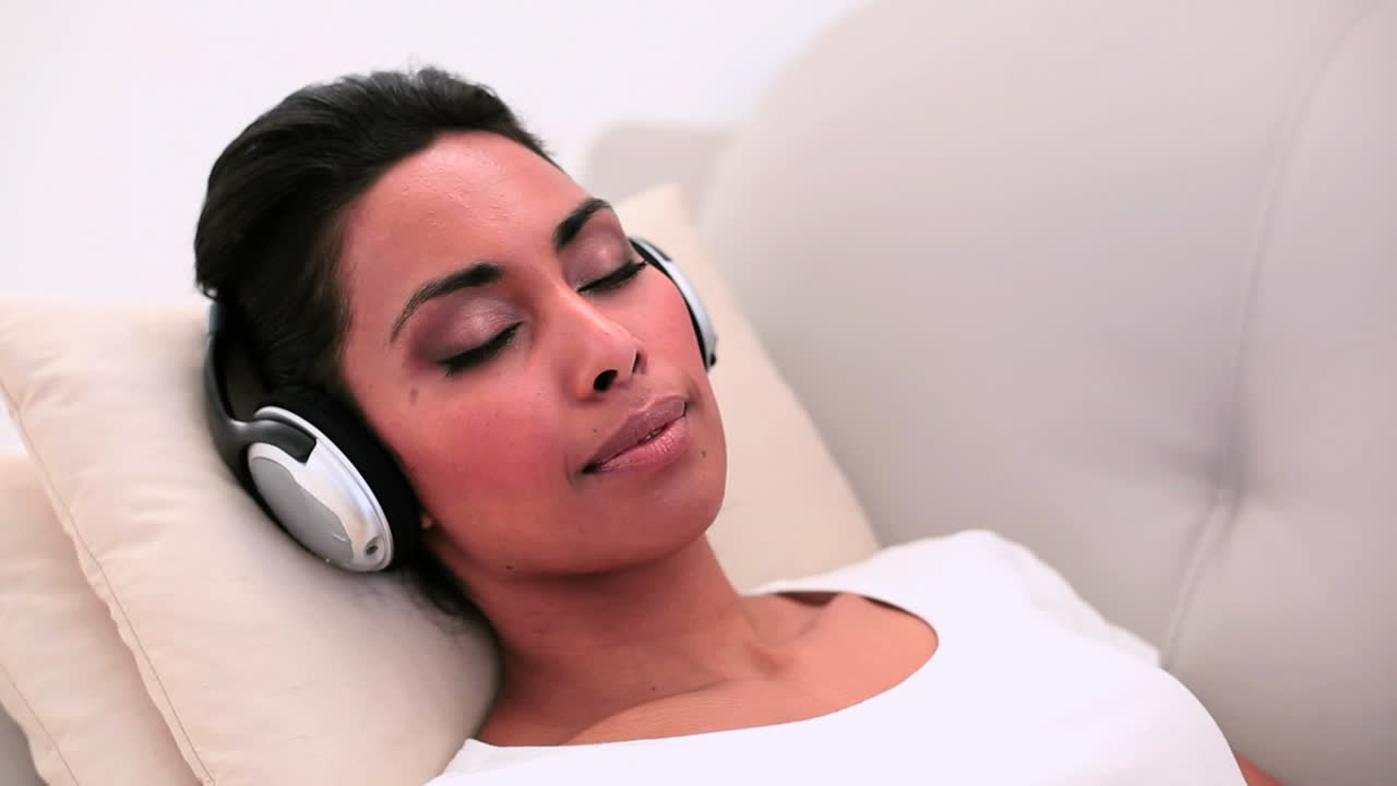 Donna attraente sdraiata sul divano che ascolta musica