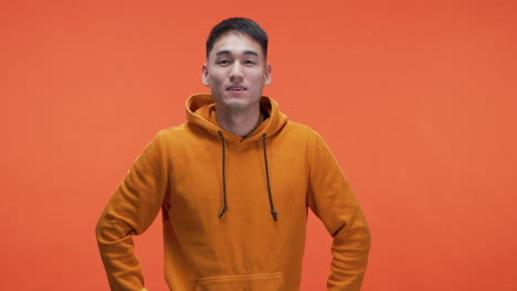 happy asian man in orange hoodie
