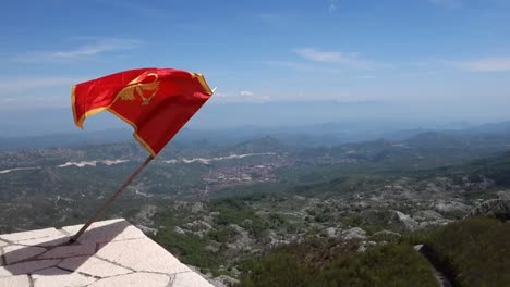montenegrin flag flying on top of mount lovcen with cetinje town on background