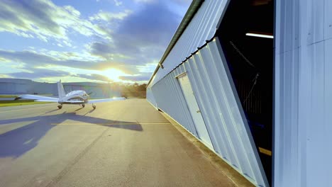 hangar door opens as sun sets, sunset with piper cherokee 180 on tarmac