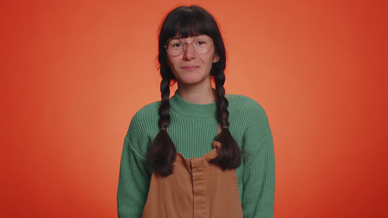 젊은 괴짜 여성이 흥분해서 미소 짓고 손가락으로 카메라를 가리키며 행운의 복권 우승자를 선택합니다.