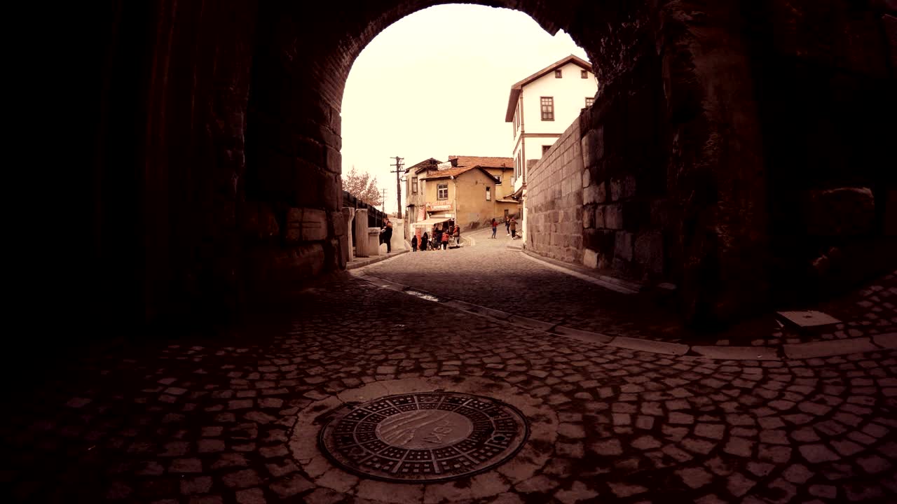 Vista attraverso un arco su una piccola strada della vecchia Ankara, persone che svolgono le loro attività