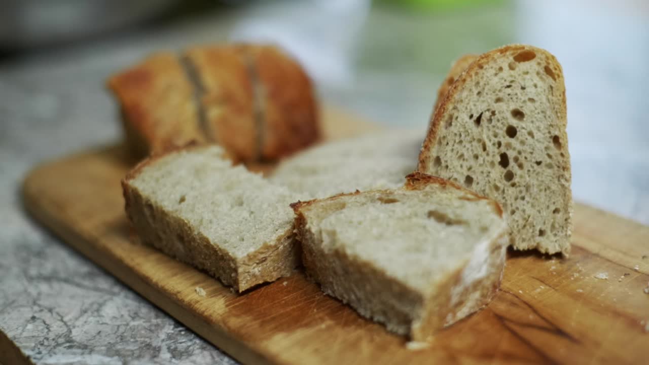 Freshly cut bread loaf presented on wooden cutting board, filmed as closeup handheld slow motion shot