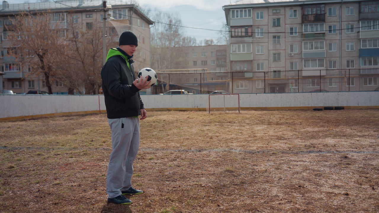 entrenamiento de fútbol en la ciudad, entorno urbano con ejercicios de balón relajados, persona practicando ejercicios informales de fútbol rodeada de arquitectura y estructuras residenciales urbanas