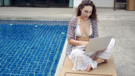 Female-tourist-using-laptop-on-lounger