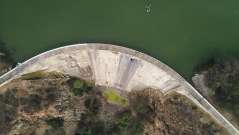 aerial: overhead drone flyover of green water dam