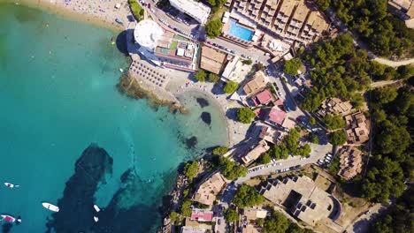 Playa-de-san-telmo,-mallorca,-with-crystal-waters-and-bustling-beach-life,-under-the-summer-sun,-aerial-view,-Spain,-in-the-Mediterranean-Sea,-balearic-islands