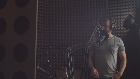 a bearded radio presenter speaks through the microphone in the cabin of a radio recording studio