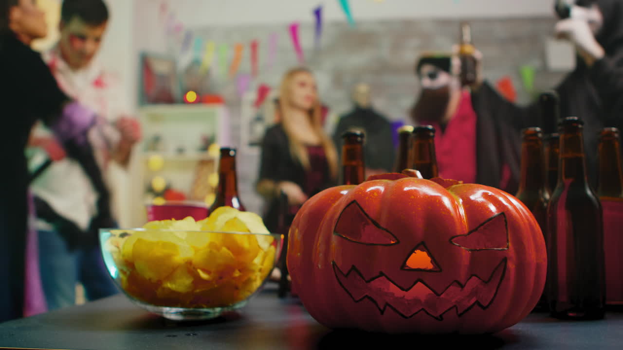 una calabaza aterradora en la fiesta mientras un grupo de personas están bailando celebrando halloween.