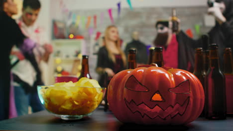 scary pumpkin on the party while group of people are dancing celebrating halloween.