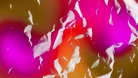 trozos de papel blanco rasgados moviéndose sobre el resplandor rojo y rosa en un fondo oscuro
