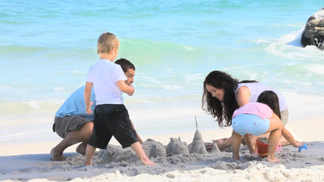 Familia-Feliz-Construyendo-Un-Castillo-De-Arena