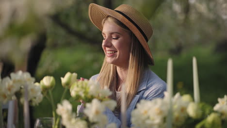 joyful woman in straw hat is sitting at table in garden laughing and joking happiness and enjoy life