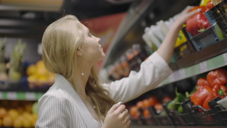 woman buying red pepper in supermarket. female hand choosing organic vegetables in grocery store. zero waste shopping and healthy lifestyle concept. slow motion