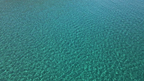 Tranquilas-Aguas-Azules-Tropicales-Y-Cristalinas-Del-Mar-De-Cerdeña-Durante-El-Verano-En-Cerdeña,-Italia---Toma-Aérea-De-Drones