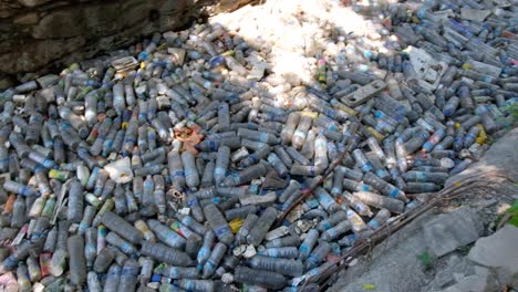 close up of thousands of plastic water bottles and rubbish polluting a stream in city centre causing environmental disaster, southeast asia