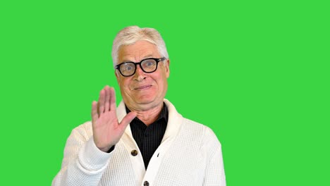 happy aged man shows a greeting sign on a green screen, chroma key