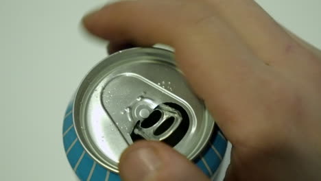 closeup view: male right hand opens pull tab on aluminum drink can