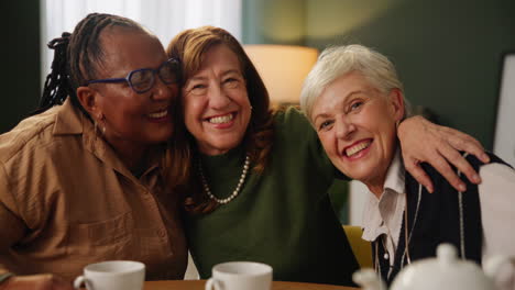 three older women friends laughing and drinking tea