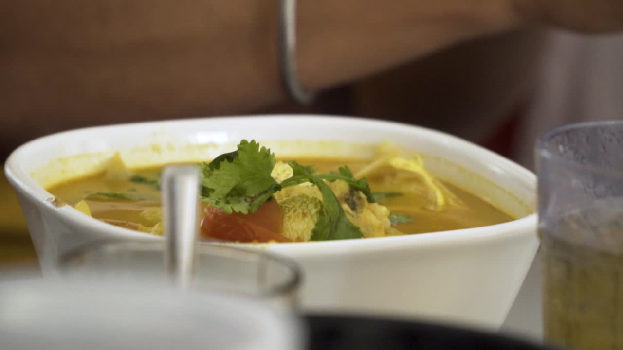 A bowl of laksa, or coconut cream curry broth noodles on a table