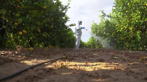 agricultor en ropa protectora rociar pesticidas