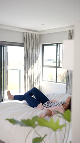 vertical video: relaxing on bed, woman in casual clothes enjoying leisure time at home